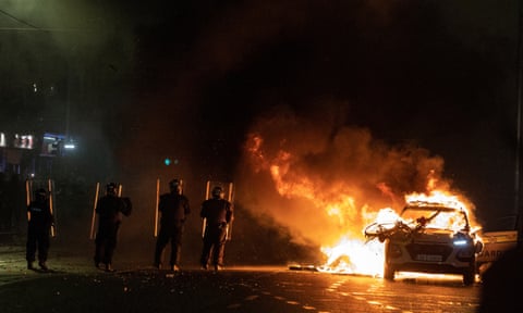 Riot police officers face down demonstrators next to a burning police car near a crime scene of a school stabbing that left several children and adults injured, in Dublin, Ireland, November 23, 2023. eiqrriheiehinv