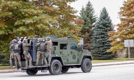 A police tactical unit makes its way down a street during the search for mass-shooting suspect in Lisbon Falls, Maine