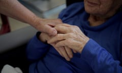 Nurse Leslie Cunich gives a resident's hand a squeeze after helping her drink at a care facility