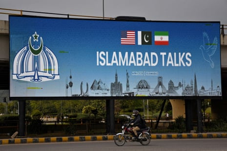 A man rides his motorbike past a billboard installed alongside a road as Pakistan prepares to host the U.S. and Iran for peace talks, in Islamabad, Pakistan.