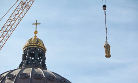 A heavy-duty crane lifts a figure of the prophet Jeremiah onto the dome.