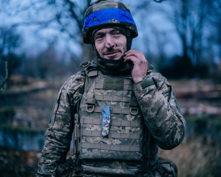 Solodenkyi is wearing camouflage combat uniform with blue tape wrapped around his helmet. He is looking slightly away from the camera