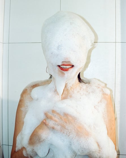 Foto de filme de uma jovem se divertindo no chuveiro com espuma de xampu.