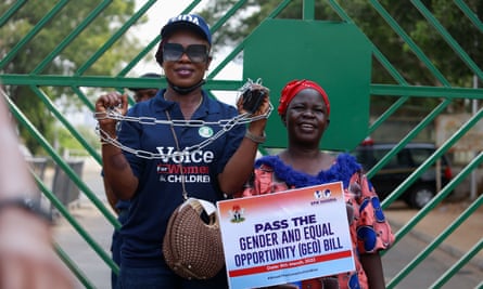 A woman shows her hands in chains while another holds a placard during a protest against legislative bias against women, in Abuja, Nigeria 8 March 2022.