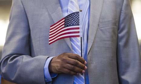 Person in gray suit holds small US flag