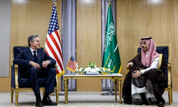 Antony Blinken, left, and Prince Faisal bin Farhan sit at a table in front of their nation's flags
