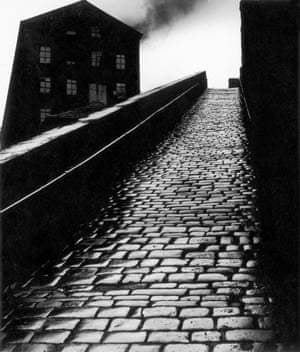 Dark industrial building with cobbled ramp in the foreground