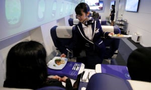 El personal, vestido de azafata, sirve aperitivos a los huéspedes de la "First Airlines", una instalación virtual de primera clase de experiencia en aerolíneas en Tokio.