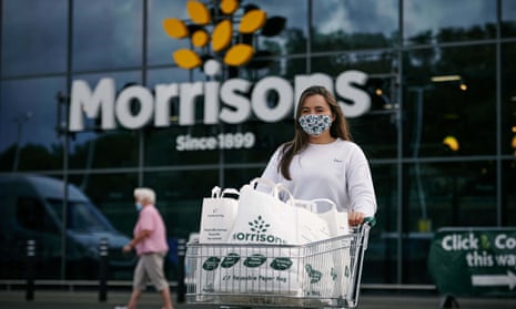 Woman wearing mask leave branch of Morrisons pushing shopped trolley with Morrisons bags
