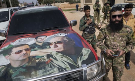 Syrian and Russian soldiers next to a car with images of Assad, his brother Maher and Putin.