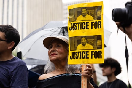 a woman holds a sign that says ‘justice for’ with a picture of a man