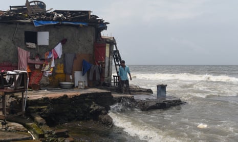 A man stands by his home next to the sea during high tide in Mumbai.