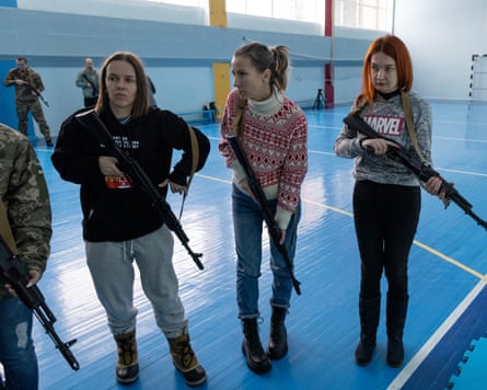 A group of women in civilian clothes holding guns in a sports hall