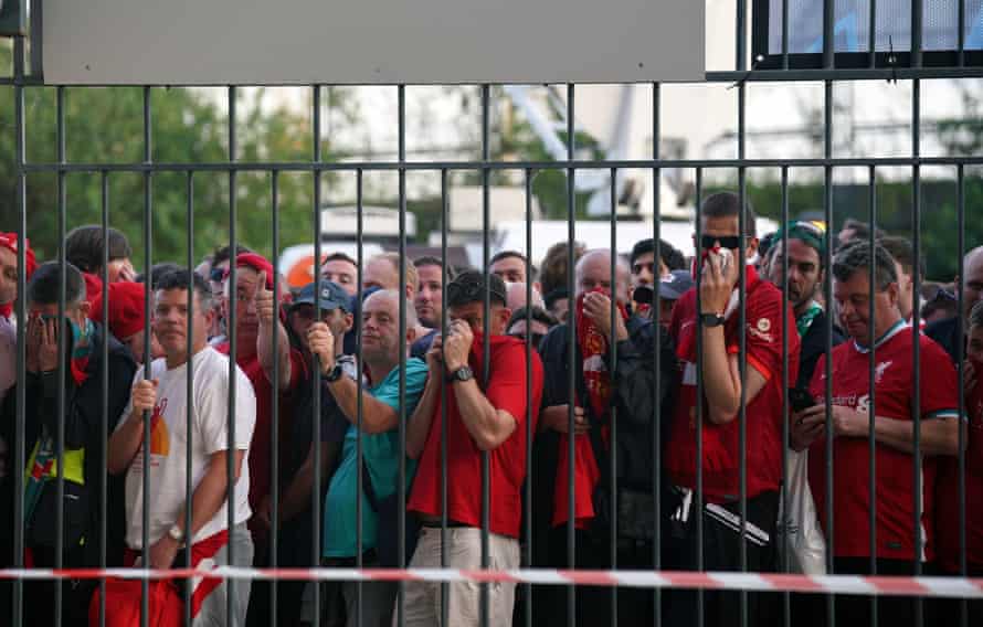 Liverpool fans cover their mouths and noses as they queue to gain entry to the stadium.