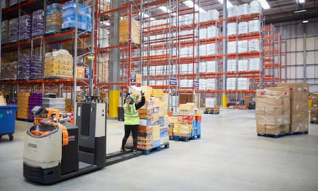 A woman works on a pallet truck in a warehouse