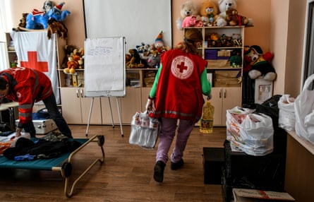 A staff member carries a pack of water bottles and a bottle of sunflower oil at the Zaporizhzhia regional office of the Ukrainian Red Cross Society.