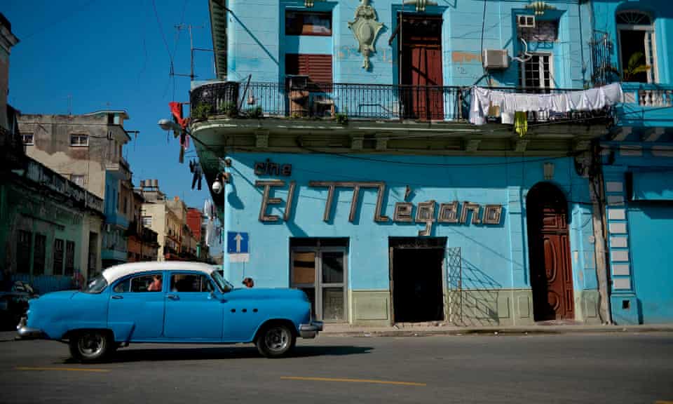 A vintage American car passes a cinema in Old Havana. 