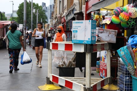 People walk down a London street in the sun