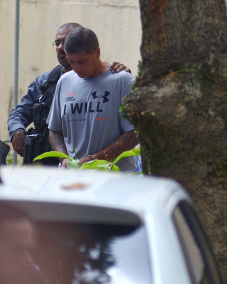 a man is led to a car by a man in uniform