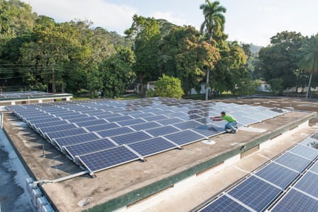 A volunteer installs solar panels on a hospital in Haiti. In California, the early success of San Benito Health’s  solar system has the facility planning for growth. Clinic officials are designing a new and bigger micro-grid.