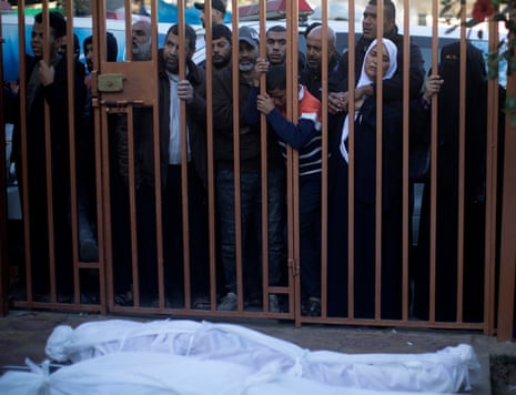 Relatives of Palestinians from the Abu Najili family, who died during Israeli airstrikes in the southern Gaza Strip, mourn near their wrapped bodies, outside Nasser hospital in Khan Yunis, southern Gaza Strip, on 3 December 2023.