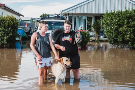 Bec First and Belinda Meaker with their dog return to check on their flooded home in Ballina