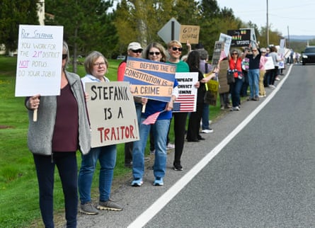 people hold signs protesting Elise Stefanik
