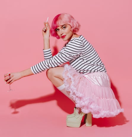 Tatty Macleod, with pink hair, pink tutu, white Breton striped shirt, very high platform shoes