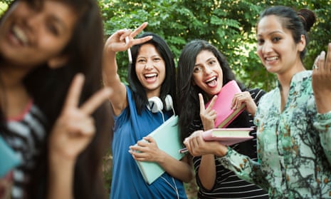 a group of young female indian students smiling and making the peace sign