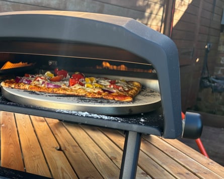 Veggie pizza being cooked outdoors in the ProCook Outdoor Pizza Oven.