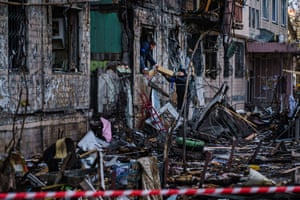 UPeople in Kyiv clean up the debris on a burned out section of a building.