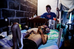 Former sugar cane worker Don Julio Lopez lies in a hospital bed with his son watching over him