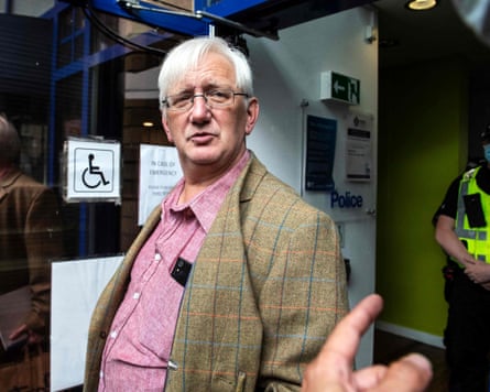 Craig Murray in pink shirt and tweed jacket in a doorway