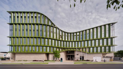 Yarrila Place in Coffs Harbour, a curved green building with many windows, apart from the first floor which is solid concrete.