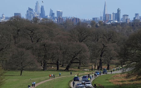 Cyclists and walkers are seen in Richmond Park with the City of London skyline behind