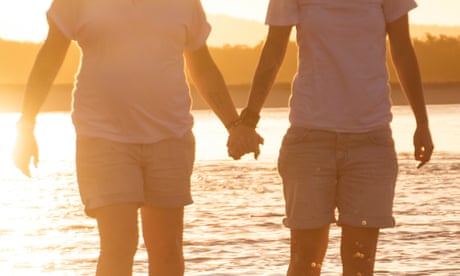 La gente se toma de la mano en la playa.