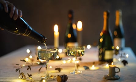 Sparkling wine is poured into a champagne glass on a decorated Christmas table