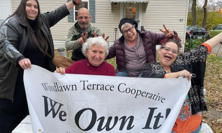 group of people hold up sign saying ‘woodlawn terrace cooperative - we own it’