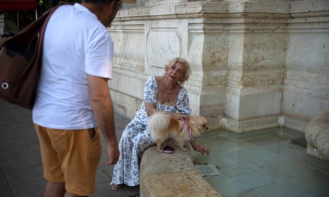 A woman gives water from a fountain to her dog in Seville as Spain experiences unseasonal temperatures.