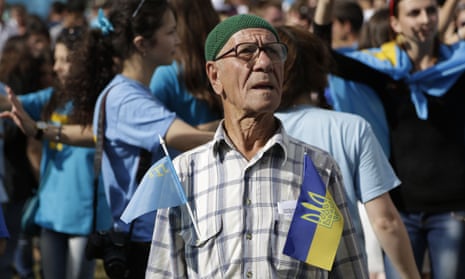 A man carries flags of Crimean Tatars and Ukraine while celebrating the Day of Crimean Tatars National Flag in Simferopol, in 2014
