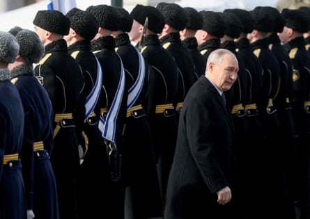 Vladimir Putin walks past a long row of Russian guards in ceremonial dress