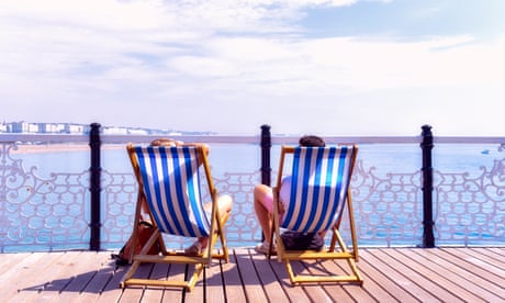 A couple seated on deckchairs enjoy the view of Brighton