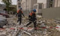 Emergency workers walk among debris in front of a residential building damaged as a result of a missile attack in Kharkiv on 14 May.