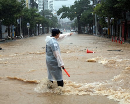 A police officer in rain gear standing in a flooded road