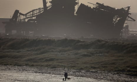 A man walks his dogs in front of the partially demolished blast furnace at the former British Steel plant near Redcar.