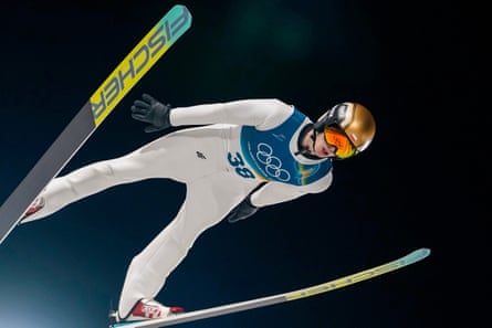 The Olympic rings are reflected on the goggles of Kacper Tomasiak, of Poland, as he soars through the air.