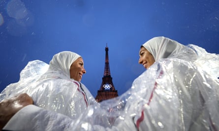 Athletes smile in front of the Eiffel Tower despite the rain.