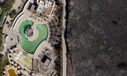 An area ravaged by wildfire stands next to a hotel on the coastline of Rhodes