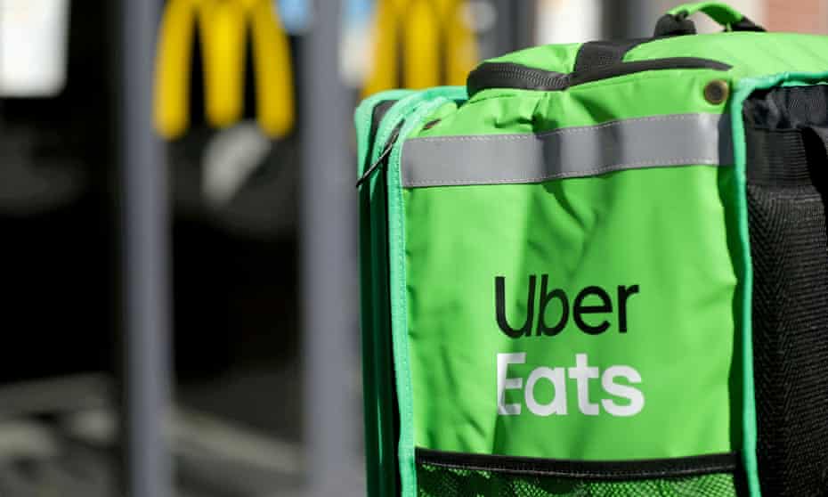 A green food warming bag carries the Uber Eats logo with a McDonald's logo in the background.