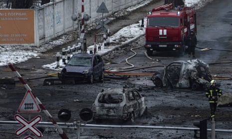 A firefighter walks in front of destroyed cars after Russian rocket attack in Kyiv.